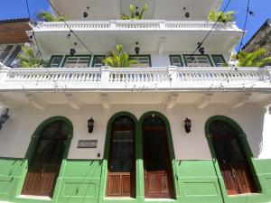 biały budynek z zielonymi drzwiami i balkonem w obiekcie AmazINN Places Rooftop and Jacuzzi V w Panamie
