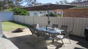 a table with chairs and an umbrella on a patio at Alka Beach House in Callala Beach +15 photos