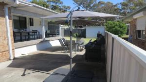 a patio with an umbrella and a table and chairs at Alka Beach House in Callala Beach