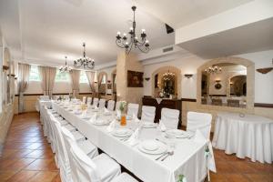 a long dining room with white tables and white chairs at Hotel Maraton in Bydgoszcz