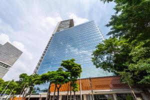 un edificio de cristal alto con árboles delante de él en Riverone 23o Andar - Apartamento Ultra Moderno de Luxo 2 Dorm + 2 Banheiros piscina borda infinita, en São Paulo