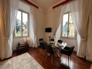 ein Wohnzimmer mit einem Tisch, Stühlen und Fenstern in der Unterkunft La tua casa nel centro di Roma in Rom