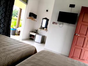 a bedroom with a bed and a flat screen tv at Haji Hassan Guesthouse in Pantai Cenang
