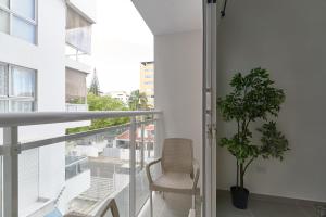 einen Balkon mit einem Stuhl und einer Topfpflanze in der Unterkunft Dom. Rep. Exclusive 2 bed Apt. Evaristo Morales in Santo Domingo