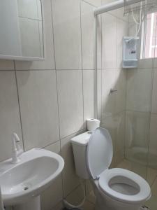 Baño blanco con aseo y lavamanos en Sol Nascente Apartamentos - Pontal do Sul en Pontal do Paraná