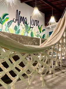 a hammock in a room with a sign on the wall at Alma Livre Pipa Casa de Praia in Pipa