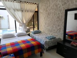 a bedroom with two beds and a mirror and a window at Casa amazilia in Leticia