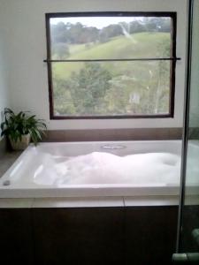 uma banheira na casa de banho com uma janela em Da Terra Brasil, Piscina e banheira dupla em Santo Antônio do Pinhal