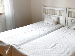 Duas camas com lençóis brancos e almofadas num quarto em Holiday home HORN VI em Horn