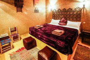 a bedroom with a large bed and a chair at Dar marco polo in Erfoud