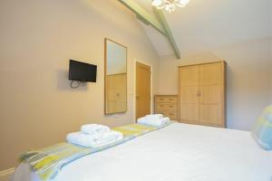 Un dormitorio con una cama blanca con toallas. en Dunlin Cottage - Lucker Steadings, en Lucker