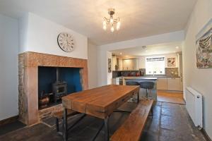 a kitchen with a wooden table and a fireplace at Beach Retreat in Seahouses
