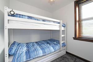 two bunk beds in a room with a window at Beach Retreat in Seahouses
