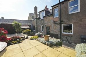 a brick house with a garden in front of it at Beach Retreat in Seahouses