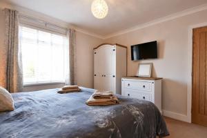 a bedroom with a bed with a television and a refrigerator at Anchor Lodge in Seahouses