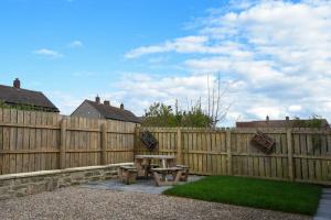 a wooden fence with a picnic table in a backyard at Anchor Lodge in Seahouses
