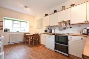 a kitchen with white cabinets and a table with chairs at Dunrovin in Beadnell