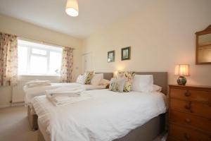 um quarto com 2 camas com lençóis brancos e uma janela em Dunrovin em Beadnell