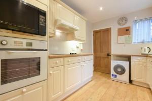 a kitchen with white cabinets and a washer and dryer at Castle View Warkworth in Warkworth
