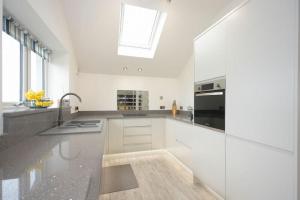 a kitchen with white cabinets and a sink and a window at Viewpoint in Alnmouth
