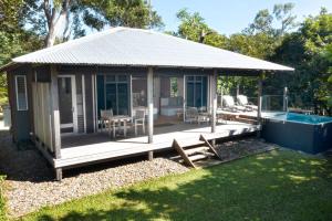 a small cabin with a deck and a swimming pool at The Bungalows in Mission Beach