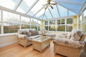 a conservatory with couches and chairs in a room with windows at Annstead House in Seahouses