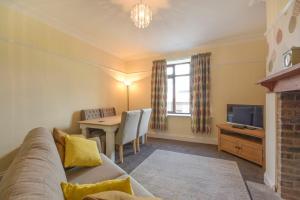 een woonkamer met een bank, een tafel en een televisie bij Dairyman's Cottage in Amble