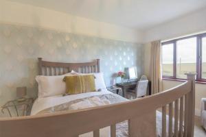 een slaapkamer met een bed, een bureau en een raam bij Dairyman's Cottage in Amble