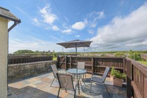 a patio with a table and chairs and an umbrella at Dairyman's Cottage in Amble