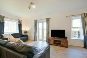 a living room with a couch and a flat screen tv at Coastal Plaice in Beadnell
