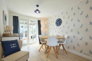 a dining room with a table and chairs and a clock on the wall at Dunford Cottage in Bamburgh