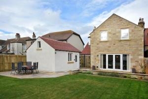 a house with a patio and a table in a yard at Bradacar in Seahouses
