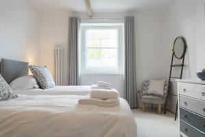 a white bedroom with two beds and a window at Treetops, Alnwick in Alnwick