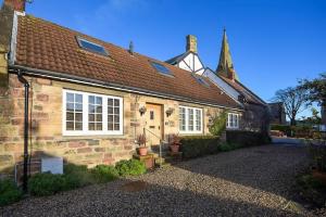 an old brick house with a church in the background at Grange Cottage in Alnmouth
