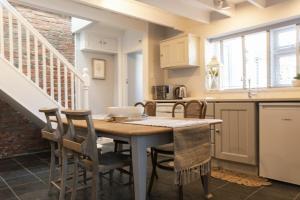 a kitchen with a table and chairs and a staircase at Creel Cottage, Craster in Craster +16 photos