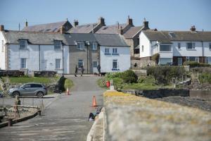 a group of houses and a street with a car at Creel Cottage, Craster in Craster