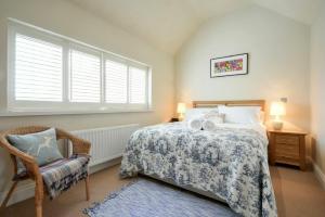 a bedroom with a bed and a chair and a window at Martins Cottage in Alnmouth