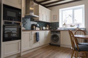 eine Küche mit einer Waschmaschine, einem Trockner und einem Tisch in der Unterkunft Kittiwake Cottage, Seahouses in Seahouses + 6 Fotos