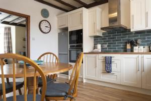 a kitchen with a table and a clock on the wall at Kittiwake Cottage, Seahouses in Seahouses