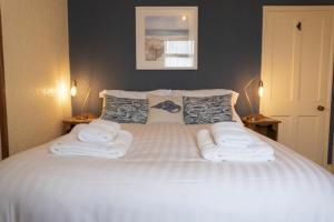 a bedroom with a white bed with towels on it at Kittiwake Cottage, Seahouses in Seahouses