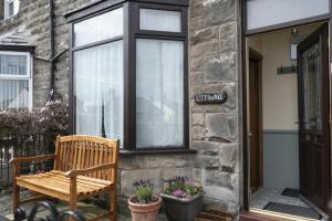 eine Holzbank vor einem Gebäude in der Unterkunft Kittiwake Cottage, Seahouses in Seahouses