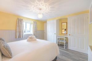 a bedroom with a large white bed and a window at Dairymaid's Cottage in Amble