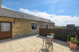 a patio with a table and chairs in front of a building at Dairymaid's Cottage in Amble