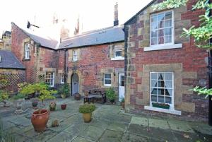 a brick house with a courtyard with potted plants at Dorothy Forster Court in Alnwick