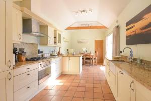 a large kitchen with white cabinets and a tile floor at Lavender Cottage Village Farm in Seahouses
