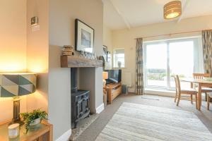 a living room with a fireplace and a dining room at Bellshill Cottage in Belford