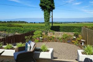 a garden with two chairs and flowers and a fence at Bellshill Cottage in Belford