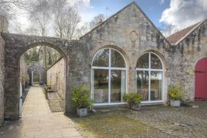 Edificio de piedra antiguo con 2 ventanas grandes en Craster Tower Coach House, en Craster