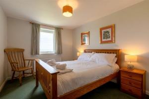 1 dormitorio con 1 cama, 1 silla y 1 ventana en Fidra, en Embleton