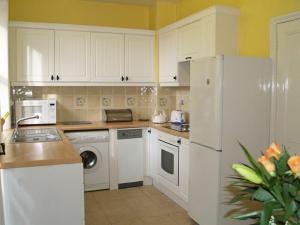 a kitchen with white cabinets and a white refrigerator at Briar Cottage in Wark